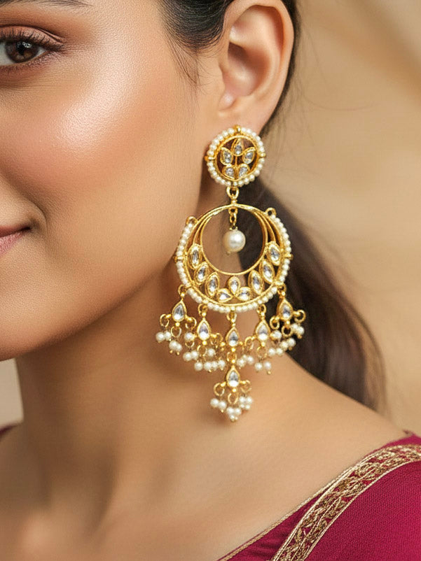 Close-up of a woman wearing an ornate traditional (Gold Polish) White Long Kundan Earrings with Kundan and Pearls. Woman styling long artificial Kundan earrings with a lehenga for a wedding. Woman wearing trendy artificial Kundan earrings for a 2026 wedding celebration in India.