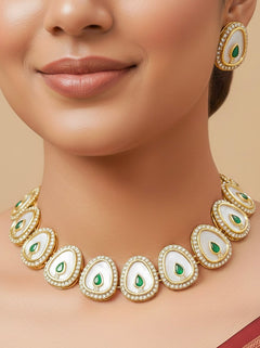 Close-up of a woman wearing an ornate traditional (Gold Polish) Green Collar Jewellery Set and Earrings with Green Colored Stone and American Diamonds. Festive celebration look enhanced with sparkling artificial American Diamond jewelry. Saree look completed with elegant artificial American Diamond jewelry for festive occasions.