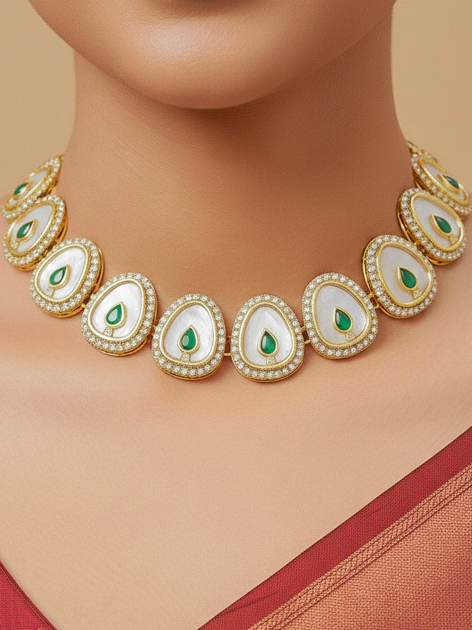 Close-up of a woman wearing an ornate traditional (Gold Polish) Green Collar Jewellery Set and Earrings with Green Colored Stone and American Diamonds. Festive celebration look enhanced with sparkling artificial American Diamond jewelry. Saree look completed with elegant artificial American Diamond jewelry for festive occasions.