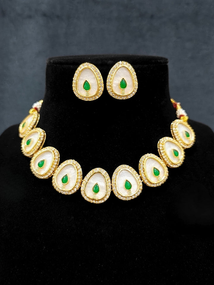 Close-up of an ornate traditional (Gold Polish) Green Collar Jewellery Set and Earrings with Green Colored Stone and American Diamonds. Festive celebration look enhanced with sparkling artificial American Diamond jewelry. Saree look completed with elegant artificial American Diamond jewelry for festive occasions.