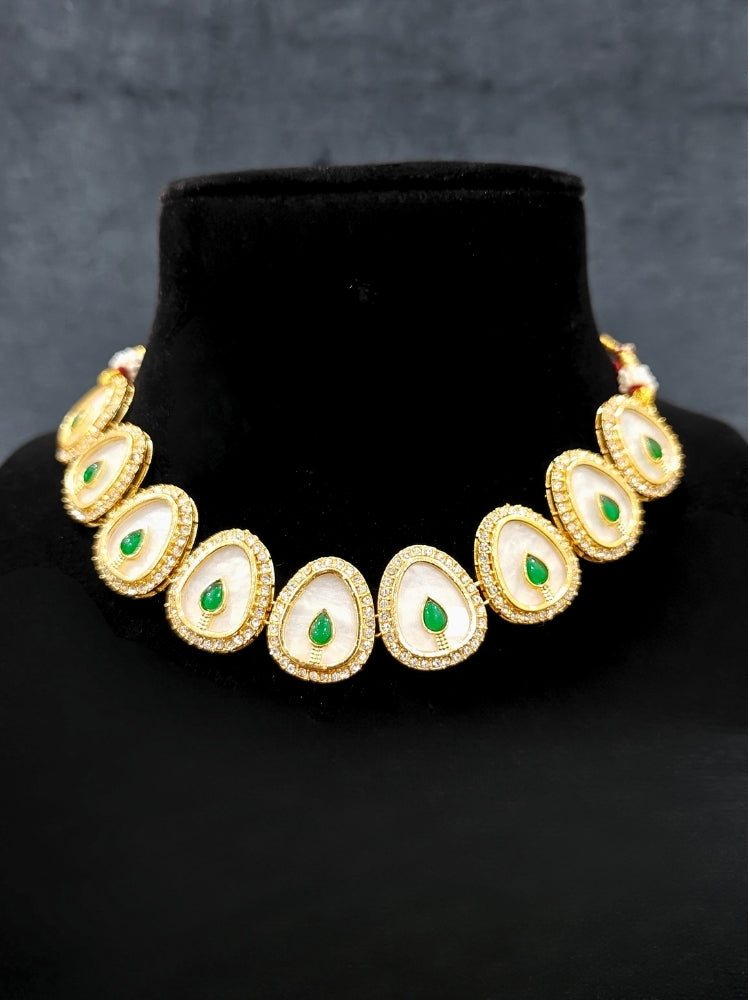 Close-up of an ornate traditional (Gold Polish) Green Collar Jewellery Set and Earrings with Green Colored Stone and American Diamonds. Festive celebration look enhanced with sparkling artificial American Diamond jewelry. Saree look completed with elegant artificial American Diamond jewelry for festive occasions.