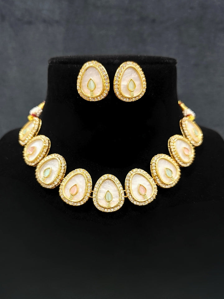 Close-up of a woman wearing an ornate traditional (Gold Polish) Mint Pink & Green Collar Jewellery Set and Earrings with Mint Pink & Green Colored Stone and American Diamonds. Festive celebration look enhanced with sparkling artificial American Diamond jewelry. Saree look completed with elegant artificial American Diamond jewelry for festive occasions.