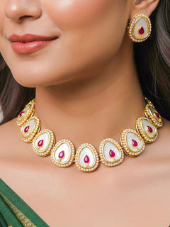 Close-up of a woman wearing an ornate traditional (Gold Polish) Red Collar Jewellery Set and Earrings with Red Colored Stone and American Diamonds. Festive celebration look enhanced with sparkling artificial American Diamond jewelry. Saree look completed with elegant artificial American Diamond jewelry for festive occasions.