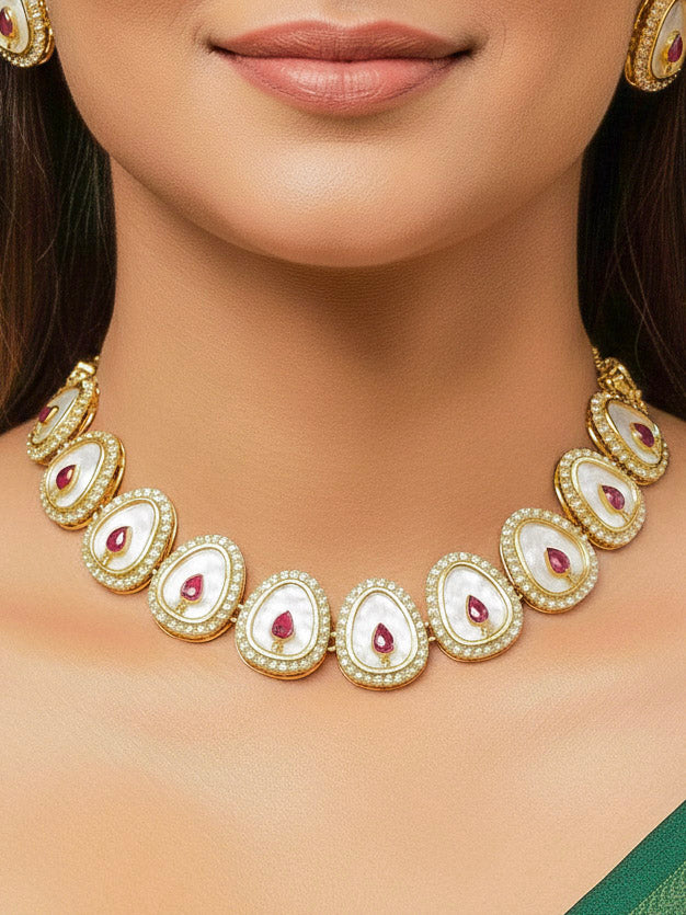 Close-up of a woman wearing an ornate traditional (Gold Polish) Red Collar Jewellery Set and Earrings with Red Colored Stone and American Diamonds. Festive celebration look enhanced with sparkling artificial American Diamond jewelry. Saree look completed with elegant artificial American Diamond jewelry for festive occasions.