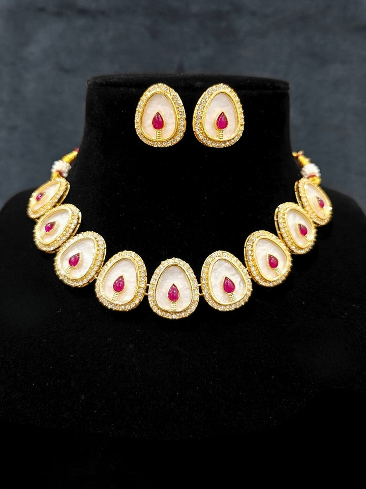 Close-up of an ornate traditional (Gold Polish) Red Collar Jewellery Set and Earrings with Red Colored Stone and American Diamonds. Festive celebration look enhanced with sparkling artificial American Diamond jewelry. Saree look completed with elegant artificial American Diamond jewelry for festive occasions.