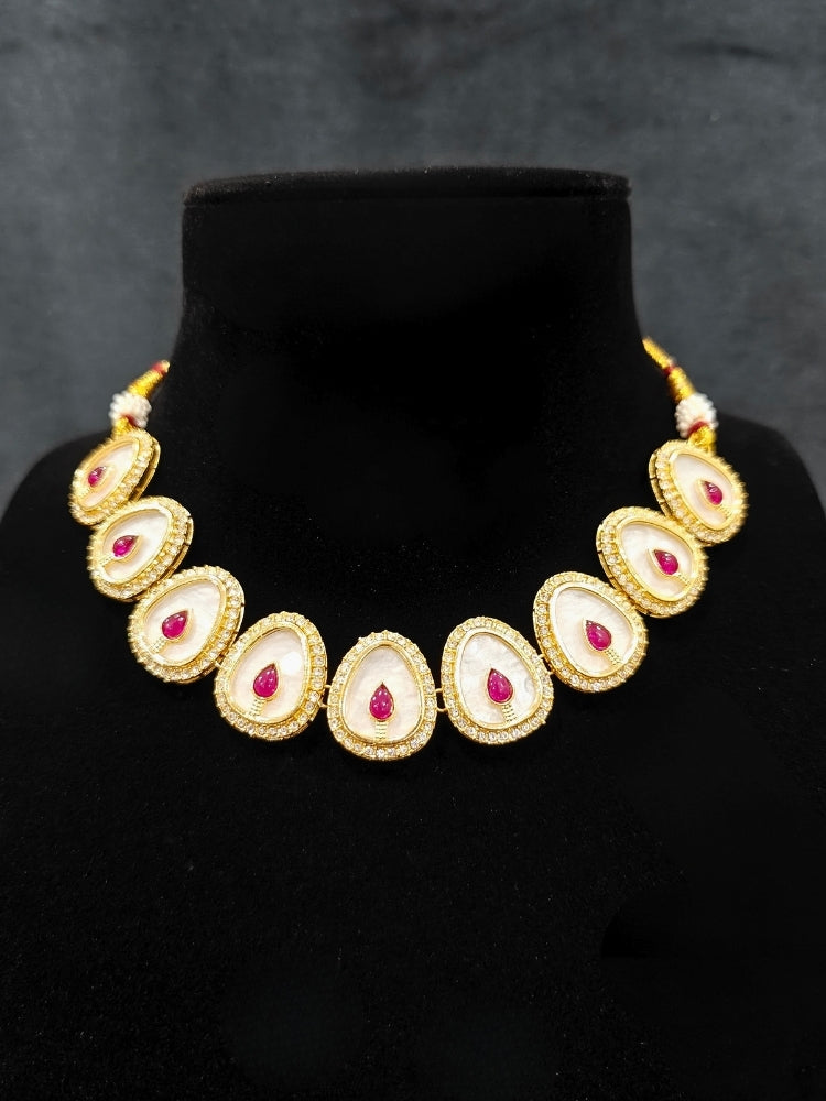 Close-up of an ornate traditional (Gold Polish) Red Collar Jewellery Set and Earrings with Red Colored Stone and American Diamonds. Festive celebration look enhanced with sparkling artificial American Diamond jewelry. Saree look completed with elegant artificial American Diamond jewelry for festive occasions.
