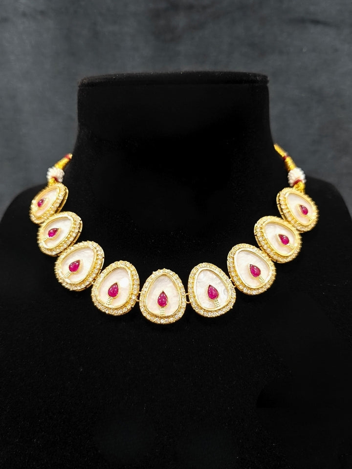 Close-up of an ornate traditional (Gold Polish) Red Collar Jewellery Set and Earrings with Red Colored Stone and American Diamonds. Festive celebration look enhanced with sparkling artificial American Diamond jewelry. Saree look completed with elegant artificial American Diamond jewelry for festive occasions.