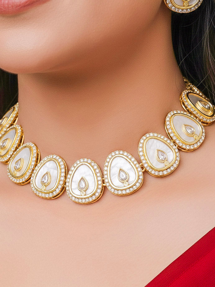 Close-up of a woman wearing an ornate traditional (Gold Polish) White Collar Jewellery Set and Earrings with American Diamond and American Diamonds. Festive celebration look enhanced with sparkling artificial American Diamond jewelry. Saree look completed with elegant artificial American Diamond jewelry for festive occasions.