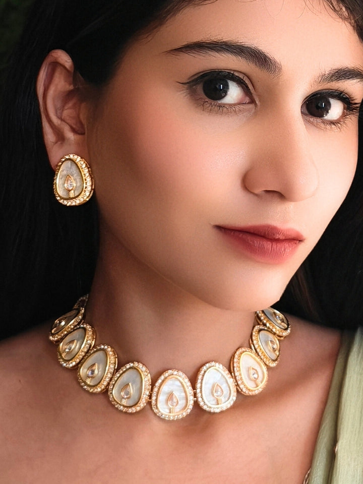 Close-up of a woman wearing an ornate traditional (Gold Polish) White Collar Jewellery Set and Earrings with American Diamond and American Diamonds. Festive celebration look enhanced with sparkling artificial American Diamond jewelry. Saree look completed with elegant artificial American Diamond jewelry for festive occasions.