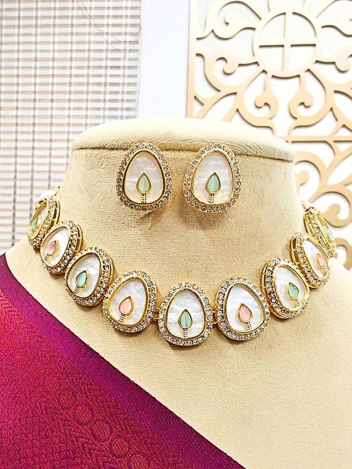The Pragati Mint Pink & Green Necklace Set features white necklace and matching earrings with white oval stones, surrounded by american diamonds, and teardrop-shaped multicolored gems in the center of each oval—perfect Wedding Ceremony Jewelry, shown on a mannequin bust.