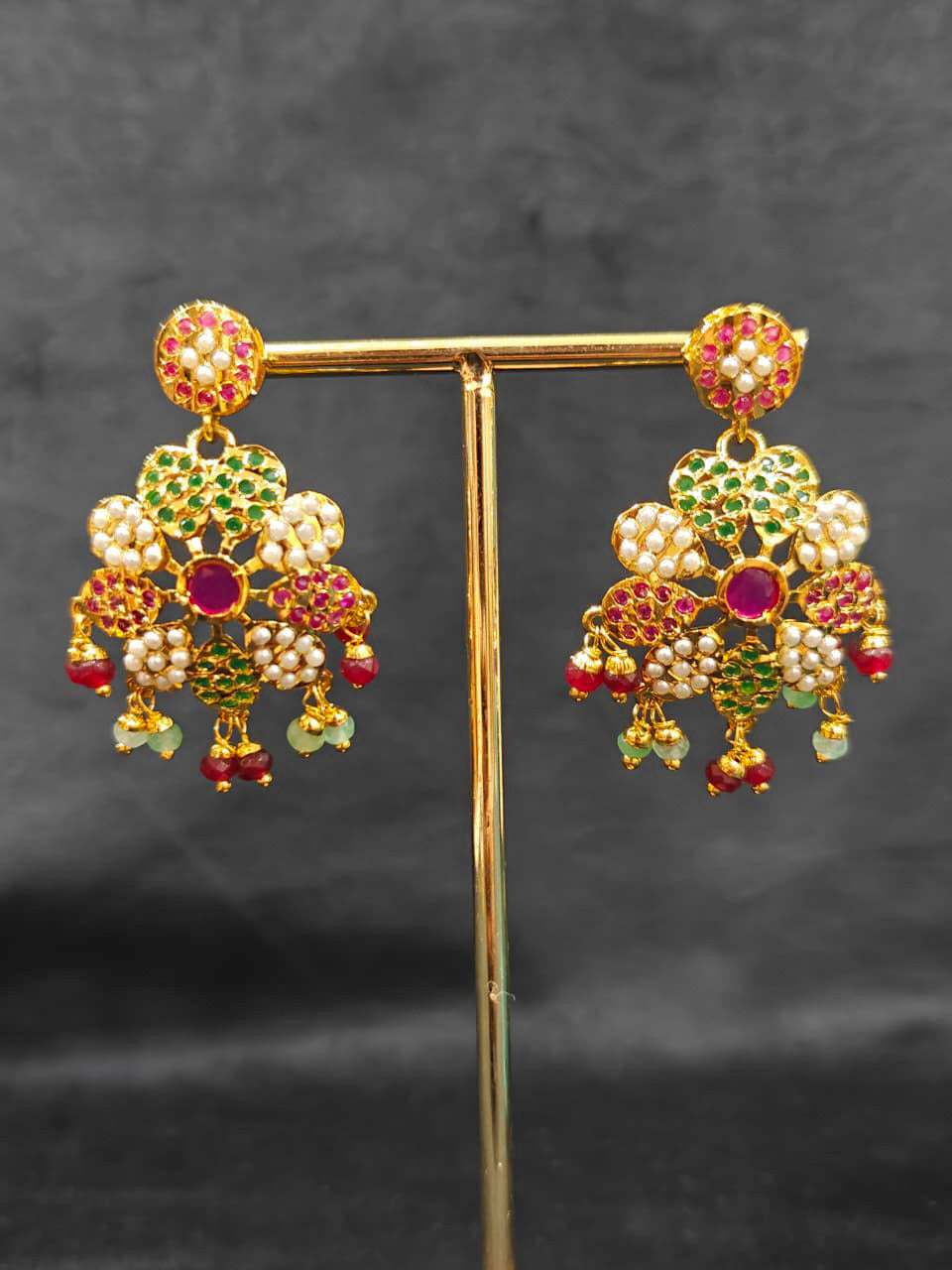 Close-up of an ornate traditional Collar Ruby Pink & Green jadau gold jewellery set and jadau earrings with beads and Color Stone. Close-up of intricate Jadau detailing in artificial jewelry. Festive celebration look featuring a Jadau artificial necklace.