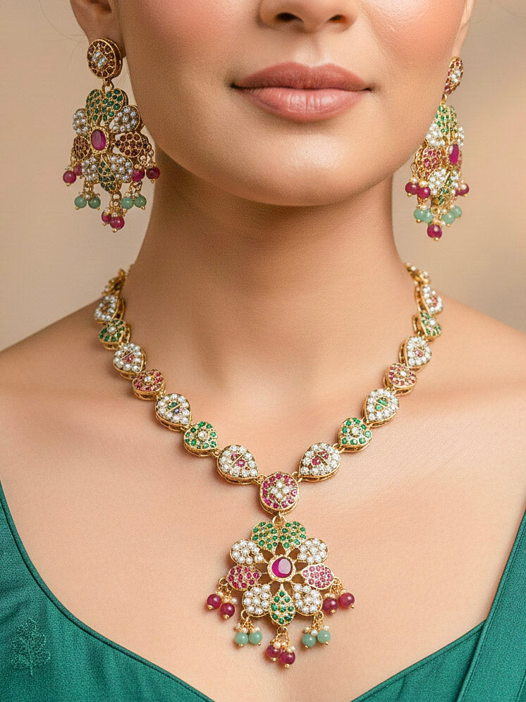 Close-up of a woman wearing an ornate handmade jadau jewelry set and earrings with ruby pink and green jadau gemstones. This is a perfect jadau jewelry set for weddings, festivals and more. Can also be worn as bridal jadau jewelry for indian weddings. 