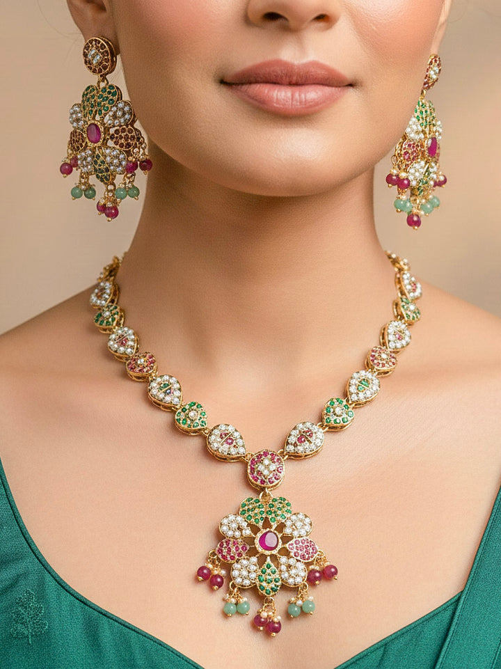 Close-up of a woman wearing an ornate handmade jadau jewelry set and earrings with ruby pink and green jadau gemstones. This is a perfect jadau jewelry set for weddings, festivals and more. Can also be worn as bridal jadau jewelry for indian weddings. 