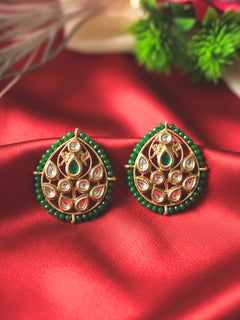 Close-up of an ornate traditional (Gold Polish) Dark Green Studs Earrings with Kundan, Crystal Beads and Green Colored Stones in Mid. Mehendi ceremony look completed with a handcrafted Kundan Studs Earrings. Festive Diwali outfit paired with a premium Kundan Studs Earrings.
