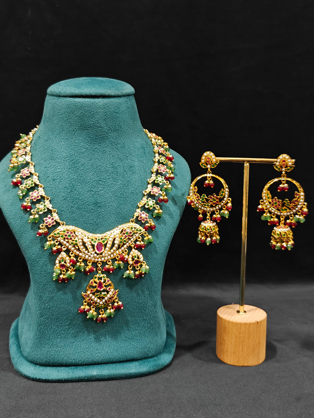 Close-up of a gold Indian traditional jadau jewellery with crystal beads and ruby pink and green jadau stones and matching jadau earrings. Festive celebration look featuring a Jadau artificial necklace.