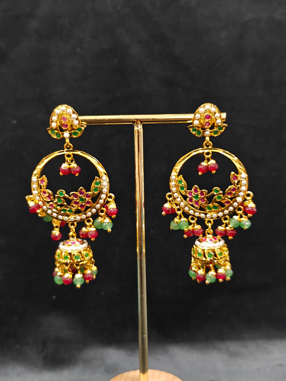 Close-up of a gold Indian traditional jadau jewellery with crystal beads and ruby pink and green jadau stones and matching jadau earrings. Festive saree look completed with a handcrafted Jadau necklace.