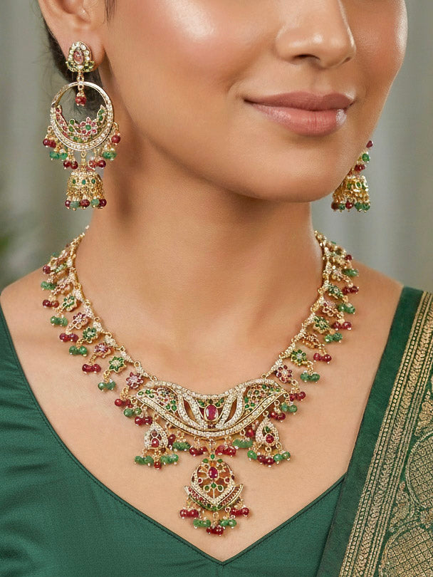 Close-up of a woman wearing a gold Indian traditional jadau jewellery with crystal beads and ruby pink and green jadau stones and matching jadau earrings. This authentic jadau jewelry set can we worn as jadau necklace set for weddings. 