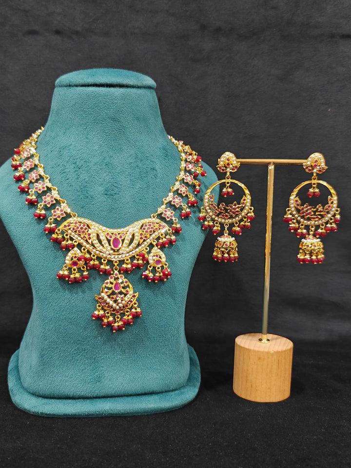Close-up of a gold Indian traditional jadau jewellery with crystals beads and ruby pink jadau stones. This authentic jadau jewelry set can we worn as jadau necklace set for weddings. Festive celebration look featuring a Jadau artificial necklace.