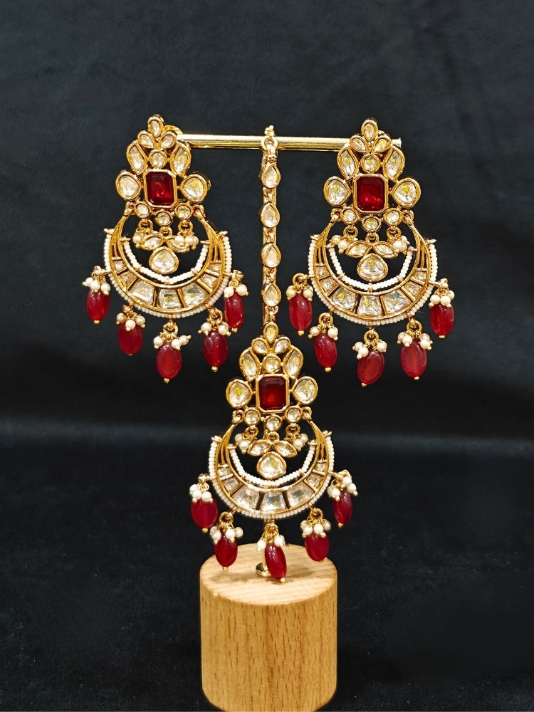 Close-up of an ornate traditional (Gold Polish) Collar jewellery set and earrings and maangtikka with Red Colored Stones, Polki, Kundan, Tumble beads and Pearls. Bride wearing a statement Polki jewelry set for wedding photos. Woman wearing trending Polki artificial jewelry for the wedding season in India.