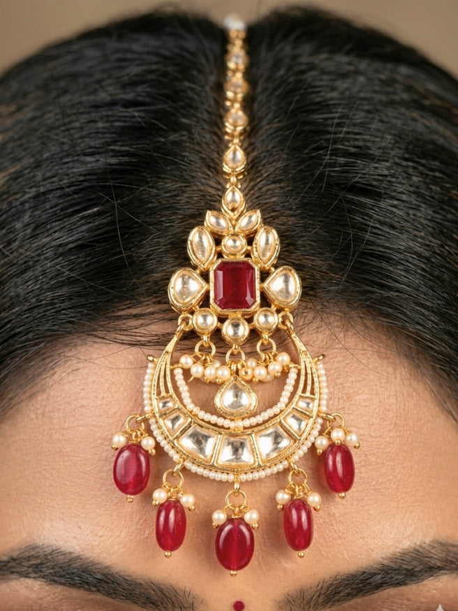 Close-up of a women wearing an ornate traditional (Gold Polish) Collar jewellery set and earrings and maangtikka with Red Colored Stones, Polki, Kundan, Tumble beads and Pearls. Bride wearing a statement Polki jewelry set for wedding photos. Woman wearing trending Polki artificial jewelry for the wedding season in India.