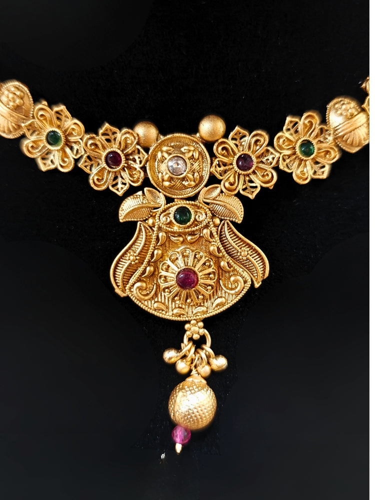 Close-up of an ornate traditional (Gold Polish) Collar jewellery set and earrings with Colored Stones. Mehendi ceremony look completed with a handcrafted Colored Stone jewelry set. Woman wearing trending Colored Stone artificial jewelry for wedding season in India.