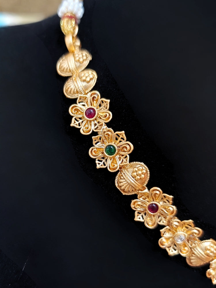 Close-up of an ornate traditional (Gold Polish) Collar jewellery set and earrings with Colored Stones. Mehendi ceremony look completed with a handcrafted Colored Stone jewelry set. Woman wearing trending Colored Stone artificial jewelry for wedding season in India.