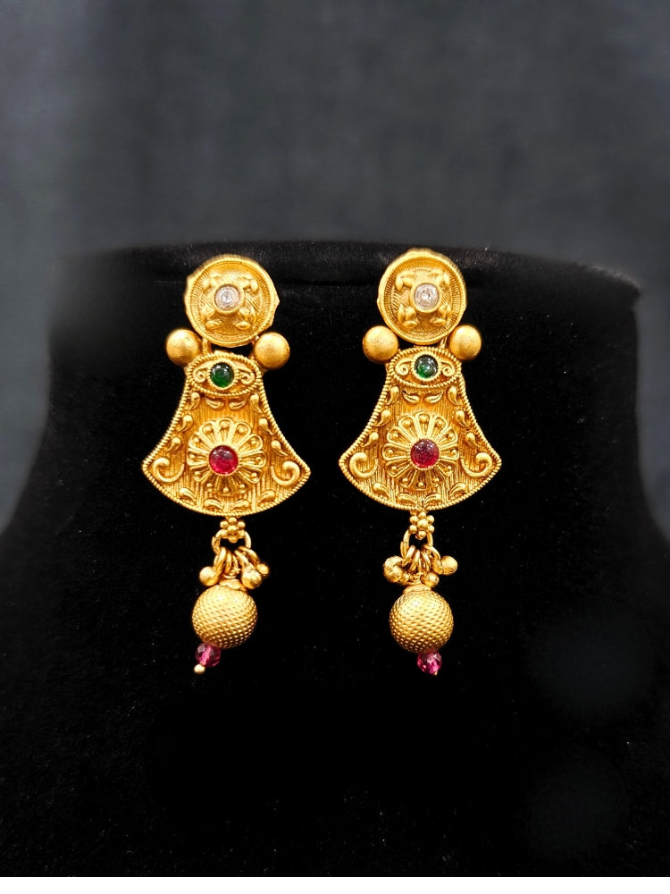 Close-up of an ornate traditional (Gold Polish) Collar jewellery set and earrings with Colored Stones. Mehendi ceremony look completed with a handcrafted Colored Stone jewelry set. Woman wearing trending Colored Stone artificial jewelry for wedding season in India.
