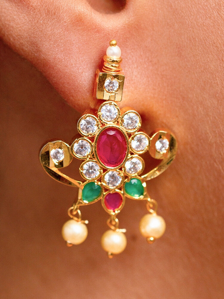Close-up of a woman wearing an ornate traditional (Gold Polish) Collar jewellery set and earrings with pearls, ruby &amp; Emerald Colored Stone and American Diamond. Festive Diwali outfit styled with an American diamond artificial necklace. Close-up shot of a high-quality American diamond artificial necklace worn for festive celebrations.