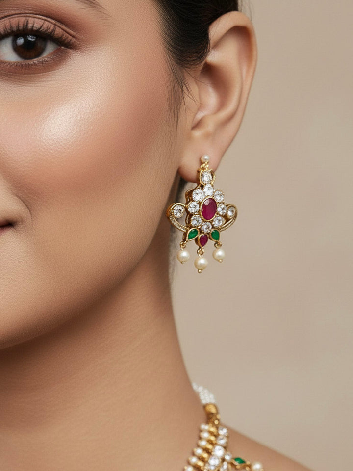 Close-up of a woman wearing an ornate traditional (Gold Polish) Collar jewellery set and earrings with pearls, ruby &amp; Emerald Colored Stone and American Diamond. Festive Diwali outfit styled with an American diamond artificial necklace. Close-up shot of a high-quality American diamond artificial necklace worn for festive celebrations.

