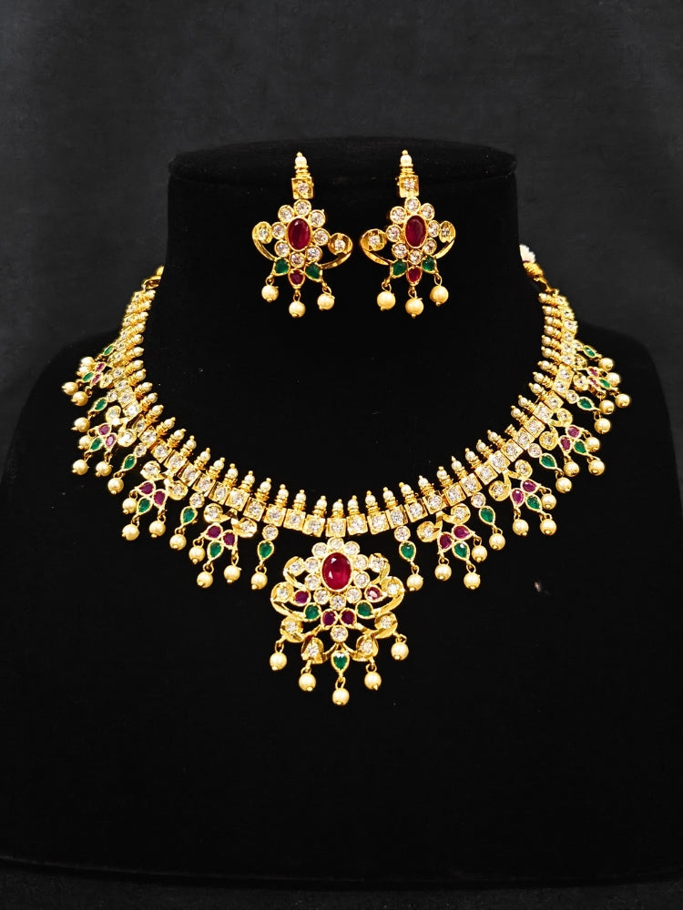 Close-up of an ornate traditional (Gold Polish) Collar jewellery set and earrings with pearls, ruby &amp; Emerald Colored Stone and American Diamond. Festive Diwali outfit styled with an American diamond artificial necklace. Close-up shot of a high-quality American diamond artificial necklace worn for festive celebrations.
