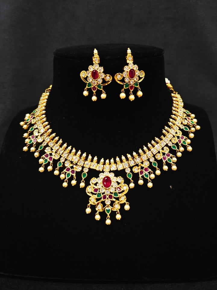 Close-up of an ornate traditional (Gold Polish) Collar jewellery set and earrings with pearls, ruby &amp; Emerald Colored Stone and American Diamond. Festive Diwali outfit styled with an American diamond artificial necklace. Close-up shot of a high-quality American diamond artificial necklace worn for festive celebrations.
