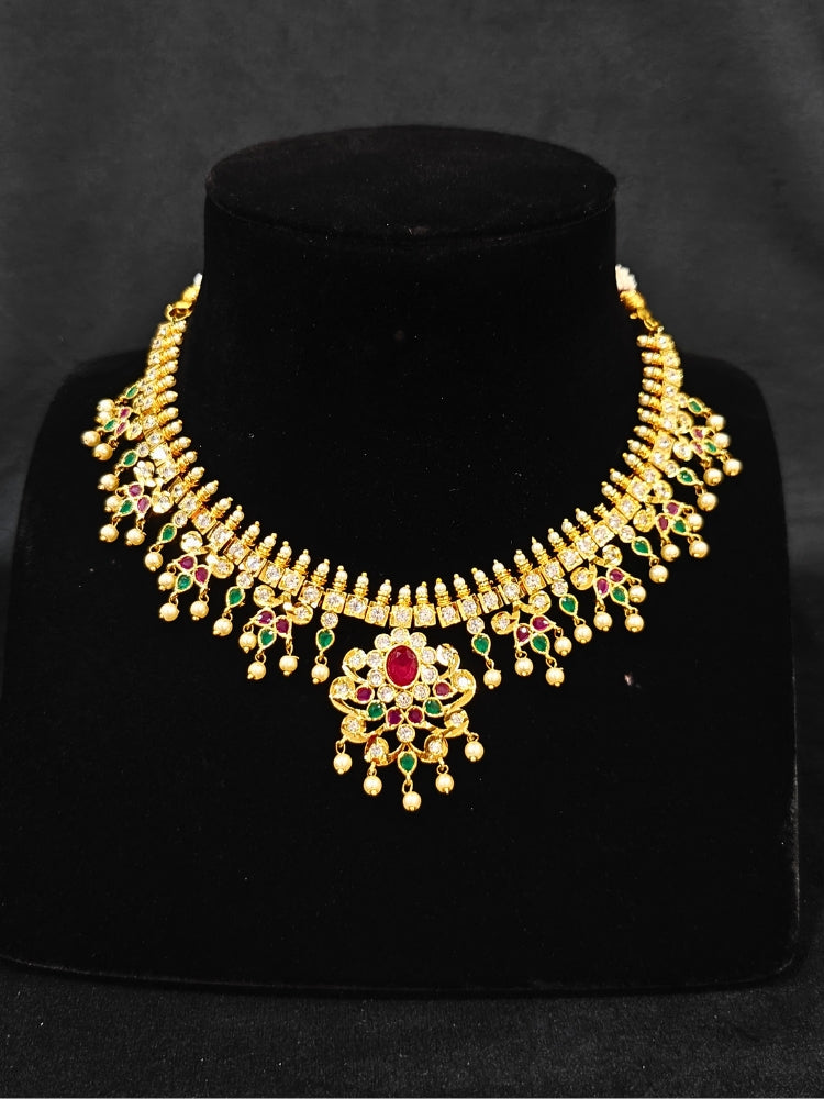 Close-up of an ornate traditional (Gold Polish) Collar jewellery set and earrings with pearls, ruby &amp; Emerald Colored Stone and American Diamond. Festive Diwali outfit styled with an American diamond artificial necklace. Close-up shot of a high-quality American diamond artificial necklace worn for festive celebrations.
