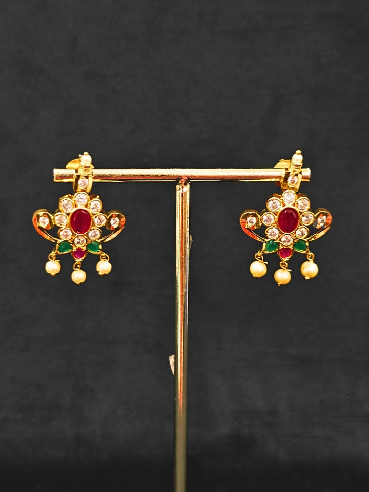 Close-up of an ornate traditional (Gold Polish) Collar jewellery set and earrings with pearls, ruby &amp; Emerald Colored Stone and American Diamond. Festive Diwali outfit styled with an American diamond artificial necklace. Close-up shot of a high-quality American diamond artificial necklace worn for festive celebrations.