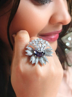 Close-up of a woman wearing an ornate Western (Silver Polish) Purple Ring with American Diamond and Purple Colored Stones. Party wear outfit completed with a lightweight American diamond Ring. Elegant wedding jewelry look featuring a premium artificial American diamond Ring.