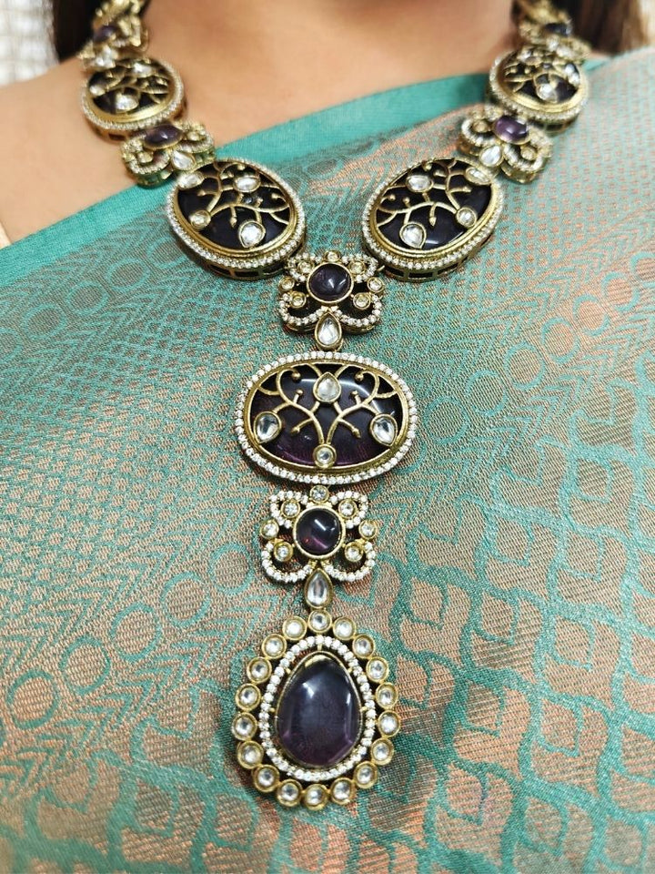 A bride-to-be wearing an exquisite artificial diamond necklace with purple colored stonen and matching earrings, designed for the perfect engagement look. This stunning artificial diamond jewelry set offers luxury and sophistication while being an affordable alternative to natural diamonds.