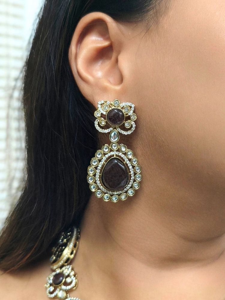 A woman in a traditional saree, wearing a gorgeous artificial diamond necklace with purple colored stone paired with diamond earrings. This artificial diamond jewelry set offers a traditional yet modern touch for Indian brides, designed to add elegance and sophistication to any occasions.