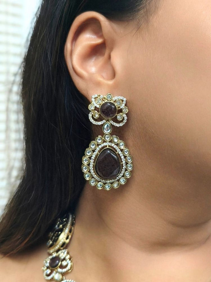 A woman in a traditional saree, wearing a gorgeous artificial diamond necklace with purple colored stone paired with diamond earrings. This artificial diamond jewelry set offers a traditional yet modern touch for Indian brides, designed to add elegance and sophistication to any occasions.
