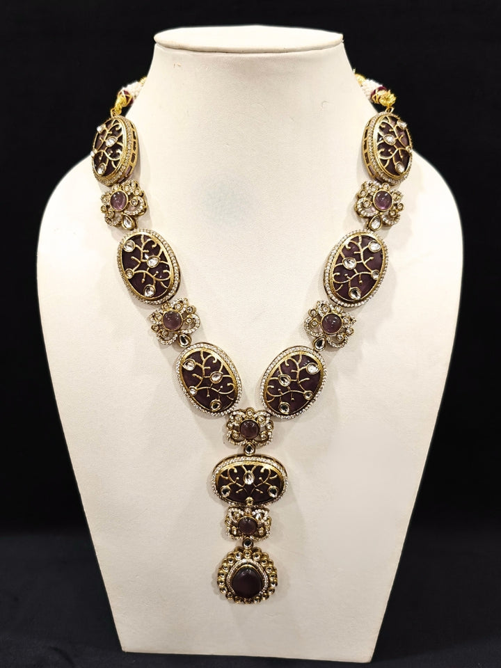 Close-up of an ornate traditional (Mehendi Gold Antique Finish) Purple long Colored Stone jewellery set and earrings with Kundan, Monalisa Stone and American Diamonds. Close-up of a premium imitation Colored Stones jewelry set styled with a aanarkali. A trending Colored Stones artificial jewelry for wedding season in India.