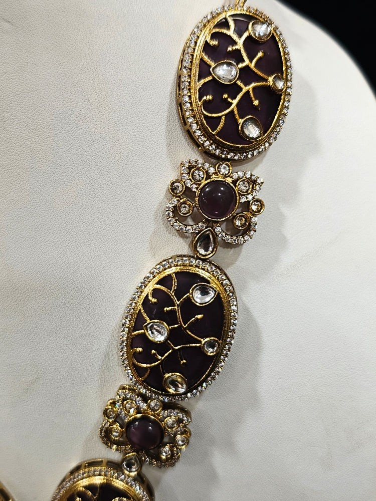 Close-up of an ornate traditional (Mehendi Gold Antique Finish) Purple long Colored Stone jewellery set and earrings with Kundan, Monalisa Stone and American Diamonds. Close-up of a premium imitation Colored Stones jewelry set styled with a aanarkali. A trending Colored Stones artificial jewelry for wedding season in India.