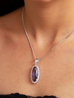 Close-up of a woman wearing an ornate Western (Silver Polish) Purple Pendant set and Earrings with American Diamond and Purple Colored Stone. Close-up of a cocktail party look featuring a premium Colored Stone Pendant Set. Party wear outfit completed with a lightweight Colored Stone Pendant set.