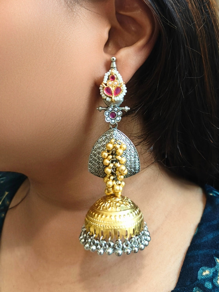Close-up of a woman wearing Raagmani Red Earrings, featuring silver, gold, and red details with kundan work and dangling ghungroos —a stunning choice to pair with your wedding ceremony dress. Oxidized earrings, german silver earrings, navratri earrings. 