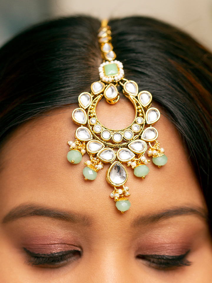 Close-up of a woman wearing an ornate traditional Green Kundan Choker jewellery set and earrings and maangtikka with Kundan, Mint green Stone, Pearls and Mint Green Crystal Beads. Bride wearing a royal Kundan artificial necklace for wedding rituals. Wedding celebration look enhanced with a statement Kundan necklace. 