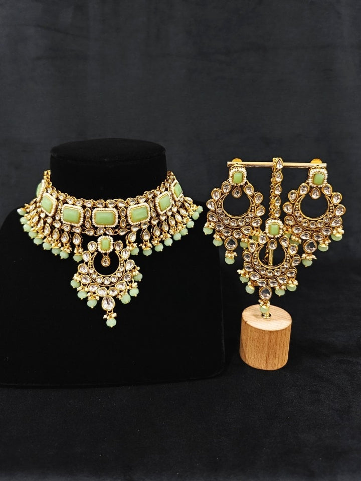 Close-up of an ornate traditional Green Kundan Choker jewellery set and earrings and maangtikka with Kundan, Mint green Stone, Pearls and Mint Green Crystal Beads. Bride wearing a royal Kundan artificial necklace for wedding rituals. Wedding celebration look enhanced with a statement Kundan necklace. 