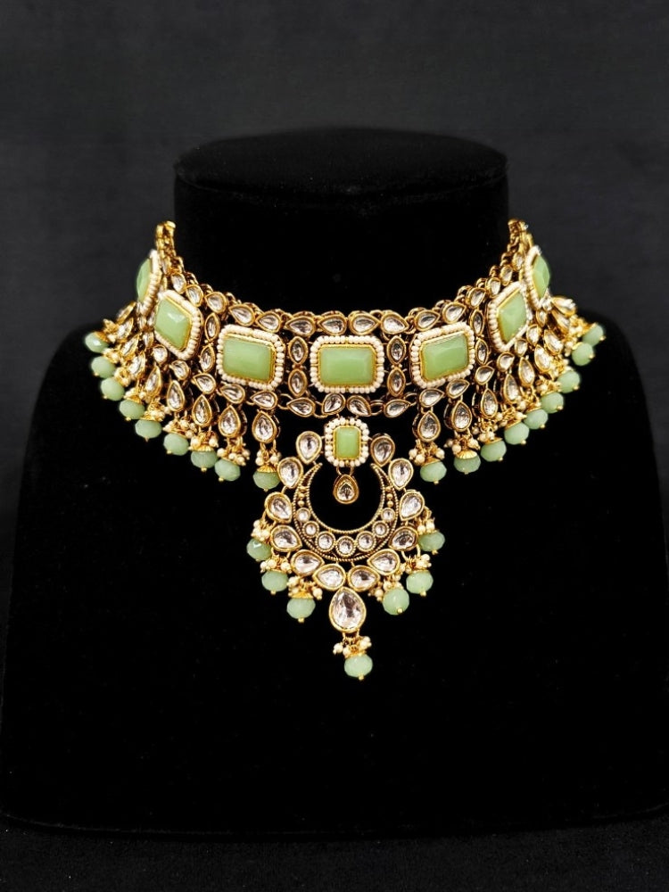 Close-up of an ornate traditional Green Kundan Choker jewellery set and earrings and maangtikka with Kundan, Mint green Stone, Pearls and Mint Green Crystal Beads. Bride wearing a royal Kundan artificial necklace for wedding rituals. Wedding celebration look enhanced with a statement Kundan necklace. 