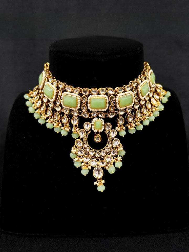 Close-up of an ornate traditional Green Kundan Choker jewellery set and earrings and maangtikka with Kundan, Mint green Stone, Pearls and Mint Green Crystal Beads. Bride wearing a royal Kundan artificial necklace for wedding rituals. Wedding celebration look enhanced with a statement Kundan necklace. 