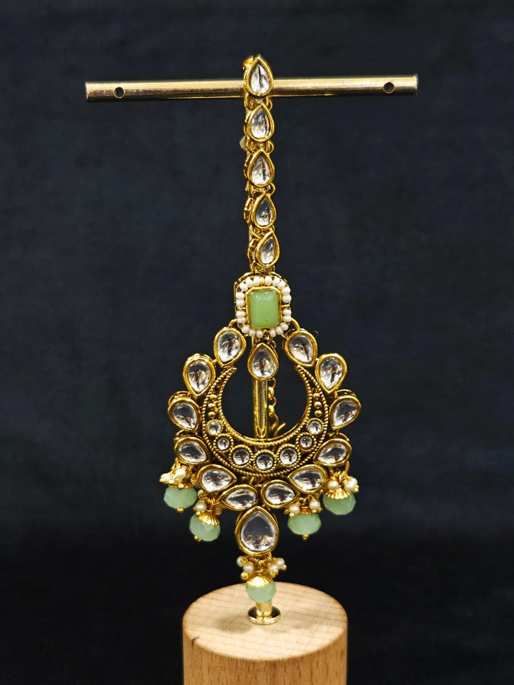 Close-up of an ornate traditional Green Kundan Choker jewellery set and earrings and maangtikka with Kundan, Mint green Stone, Pearls and Mint Green Crystal Beads. Bride wearing a royal Kundan artificial necklace for wedding rituals. Wedding celebration look enhanced with a statement Kundan necklace. 
