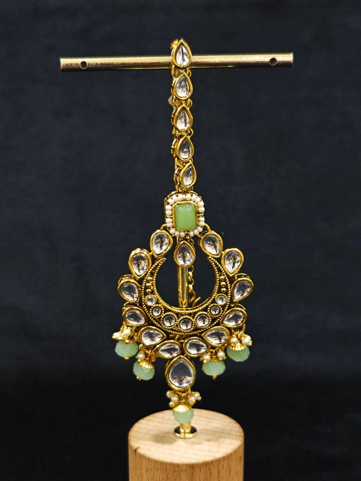 Close-up of an ornate traditional Green Kundan Choker jewellery set and earrings and maangtikka with Kundan, Mint green Stone, Pearls and Mint Green Crystal Beads. Bride wearing a royal Kundan artificial necklace for wedding rituals. Wedding celebration look enhanced with a statement Kundan necklace. 