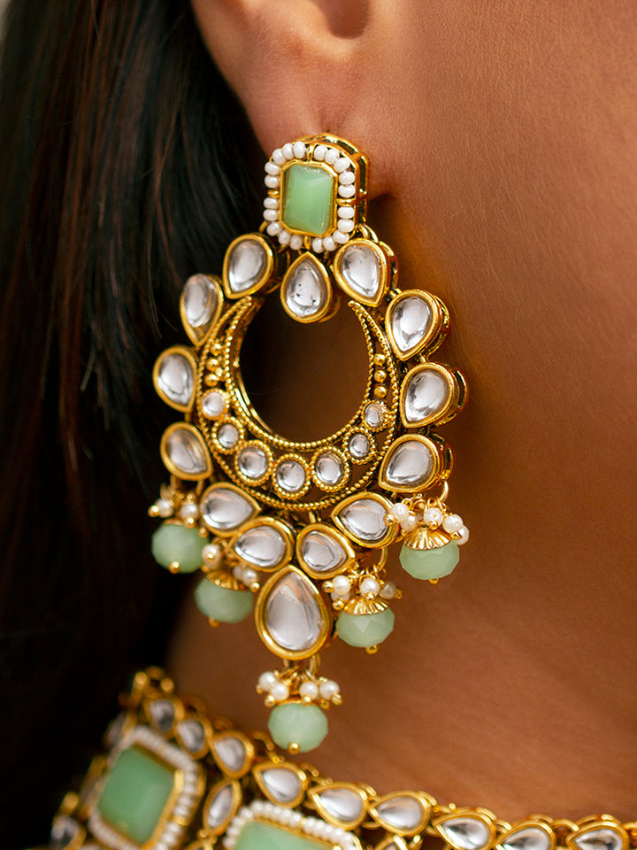 Close-up of a woman wearing an ornate traditional Green Kundan Choker jewellery set and earrings and maangtikka with Kundan, Mint green Stone, Pearls and Mint Green Crystal Beads. Bride wearing a royal Kundan artificial necklace for wedding rituals. Wedding celebration look enhanced with a statement Kundan necklace. 