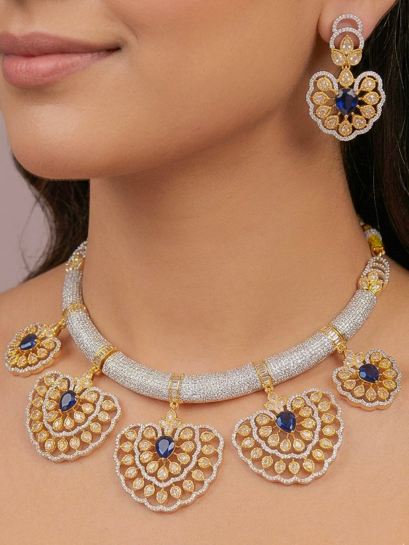 Close-up of a woman wearing an ornate Western American diamond Raizel Blue Necklace Set (Dual Tone) Collar jewellery set and earrings with Colored Stone and American Diamond. Bride-to-be styled in a premium American diamond artificial necklace for her reception party.