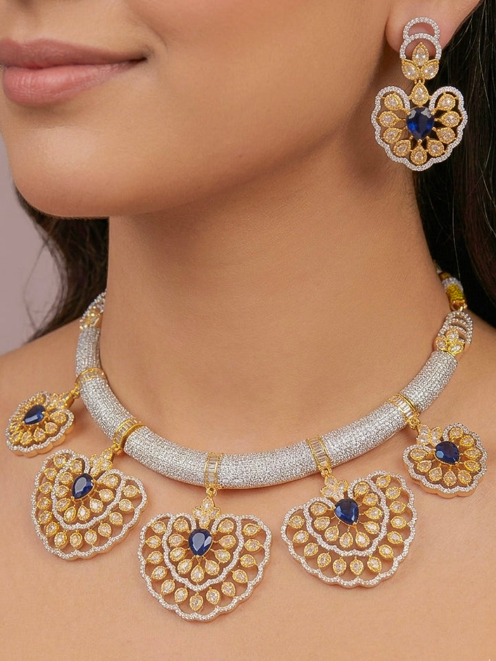 Close-up of a woman wearing an ornate Western American diamond Raizel Blue Necklace Set (Dual Tone) Collar jewellery set and earrings with Colored Stone and American Diamond. Bride-to-be styled in a premium American diamond artificial necklace for her reception party.